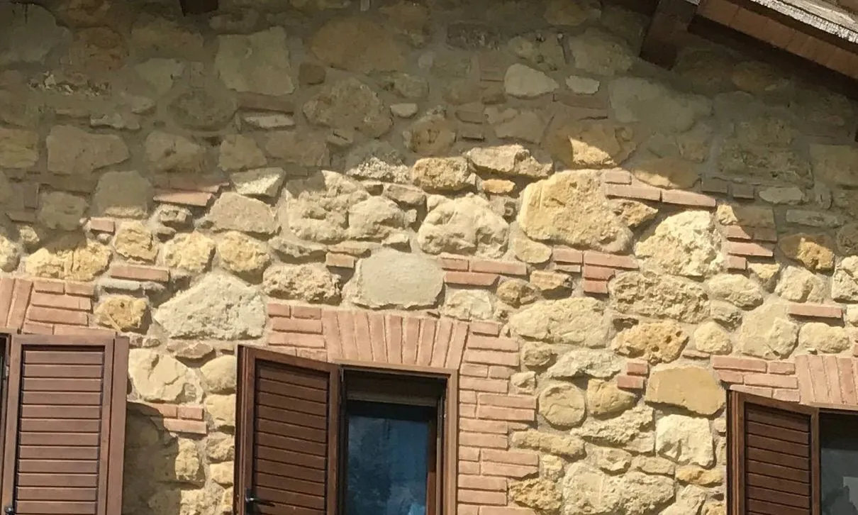 A timber-shuttered window set into the hand-laid stone wall