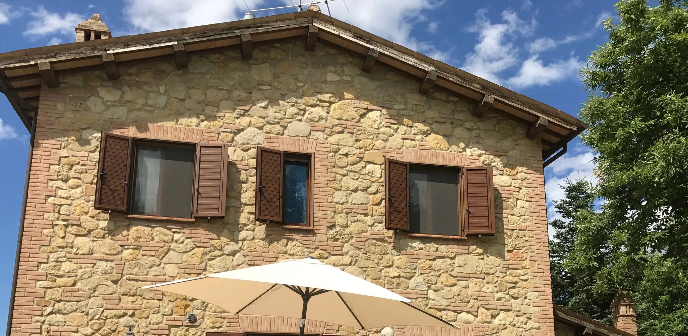 The restored stone façade with timber shutters under a blue summer sky