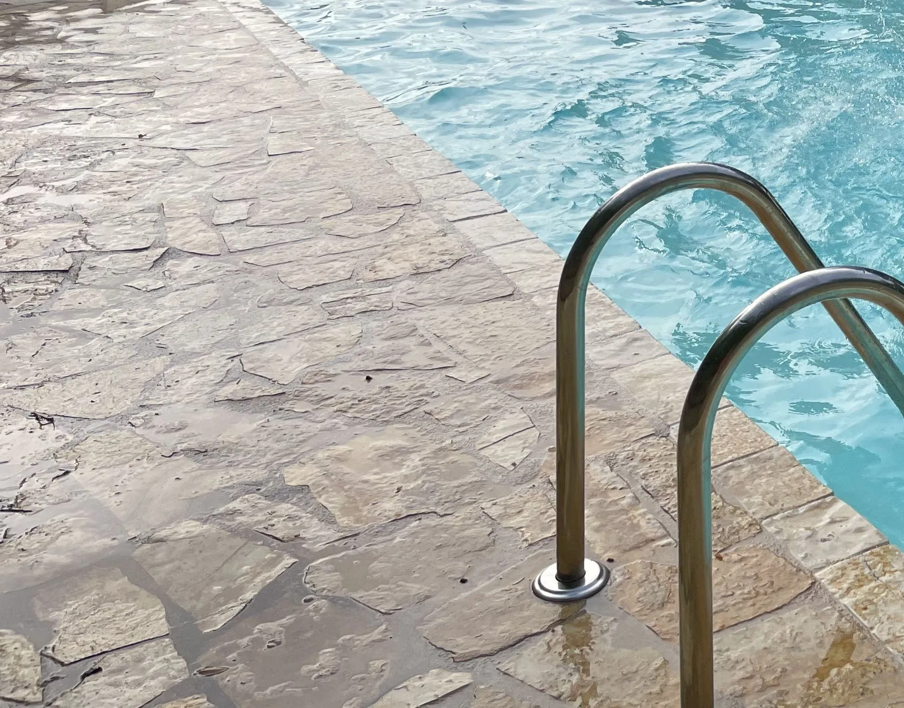 Clear turquoise water and warm stone paving at the edge of the private pool