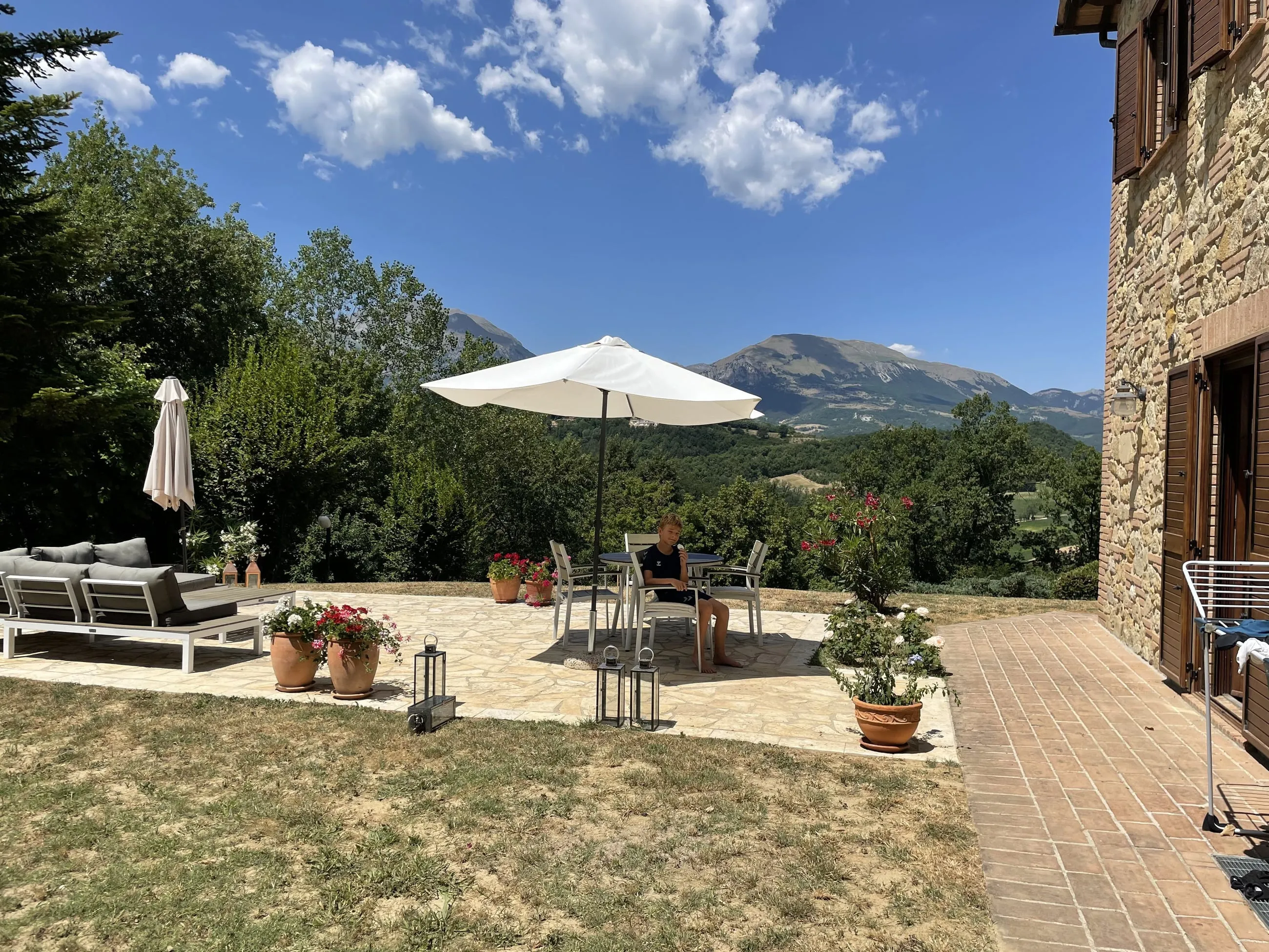 Sun terrace with parasol and potted oleander looking out over the mountain valley
